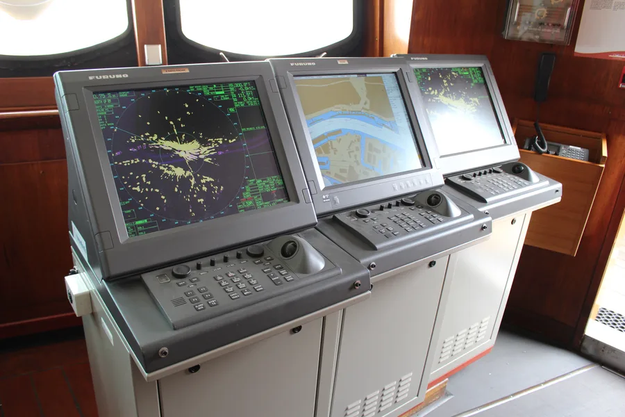 A ship's bridge with ECDIS and radar equipment operated by certified navigation and survey personnel