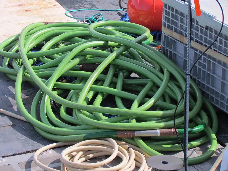 A green multichannel seismic streamer coiled on the deck of a research vessel